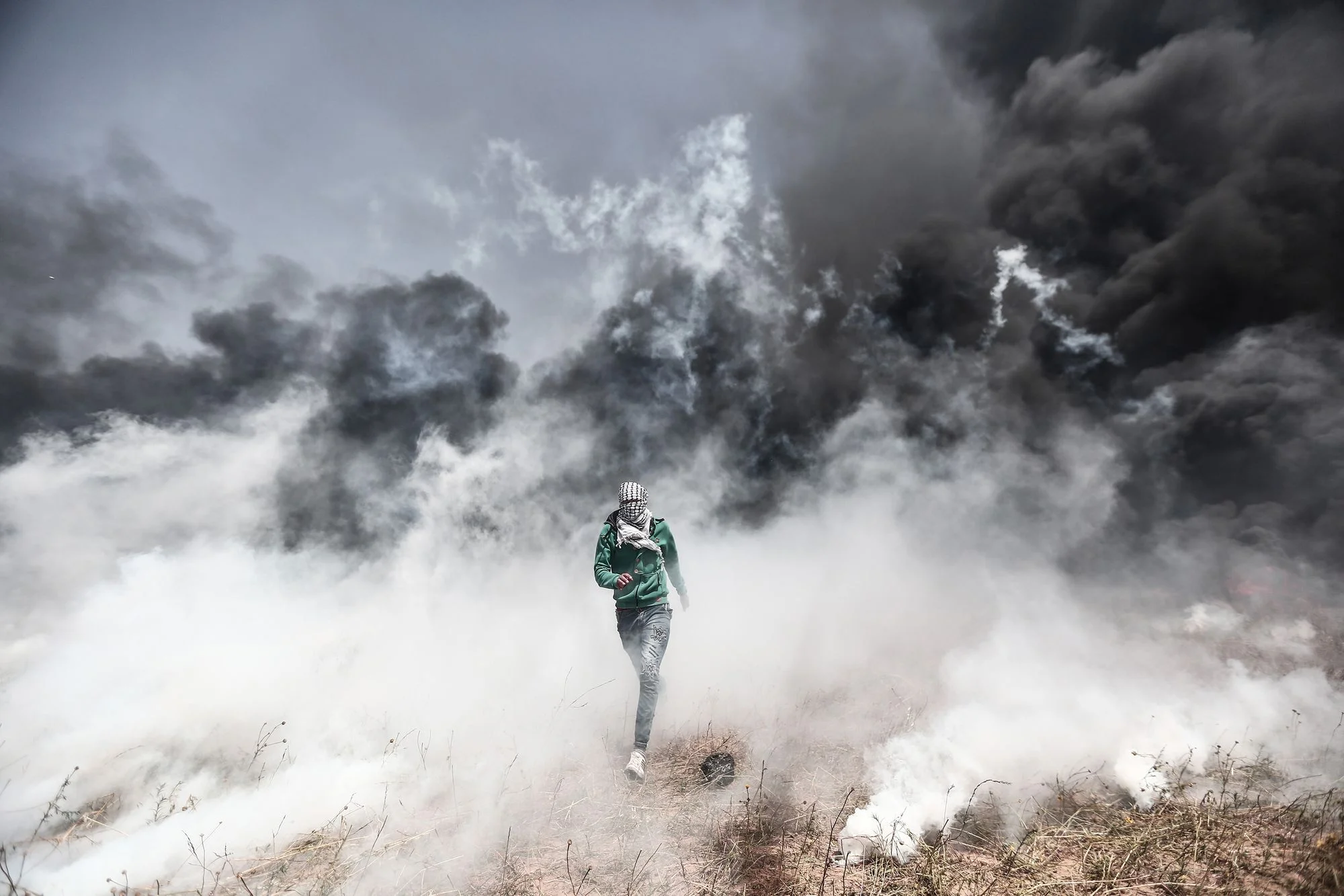 KHAN YUNIS, GAZA - APRIL 6: A Palestinian demonstrator escapes heavy smoke as Israeli soldiers fire several gas bombs during his participation in the 'Great March of Return,' despite Israel's threats near the Gaza-Israel border in Khan Yunis, Gaza on April 06, 2018. Demonstration against Israel's blockade of the Gaza Strip started taking place 11 years ago. Mustafa Hassona/Anadolu Agency