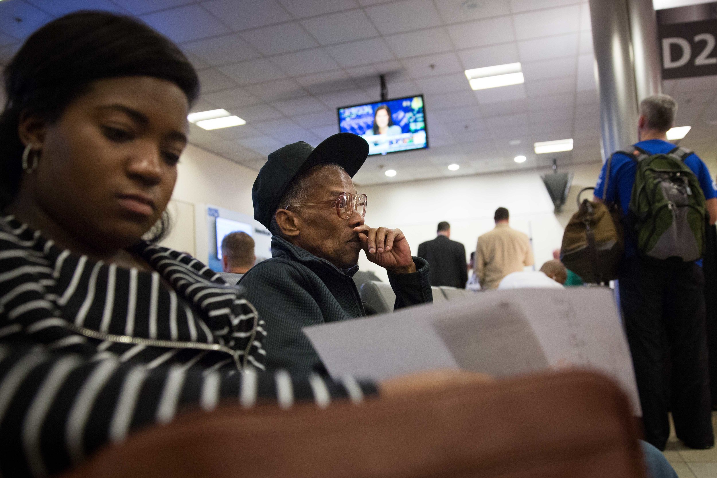 Ronald sits at his gate at the Atlanta International Airport waiting for his flight to Philadelphia with his social worker. 