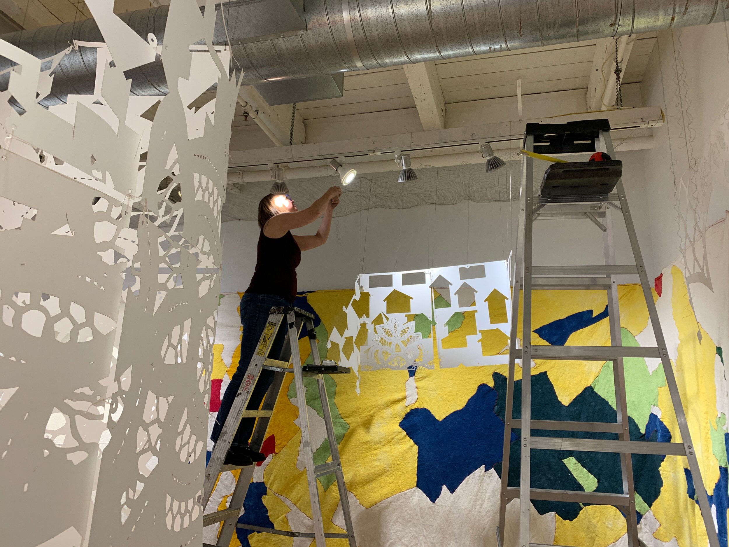 The artist hanging panels during the installation of the piece.