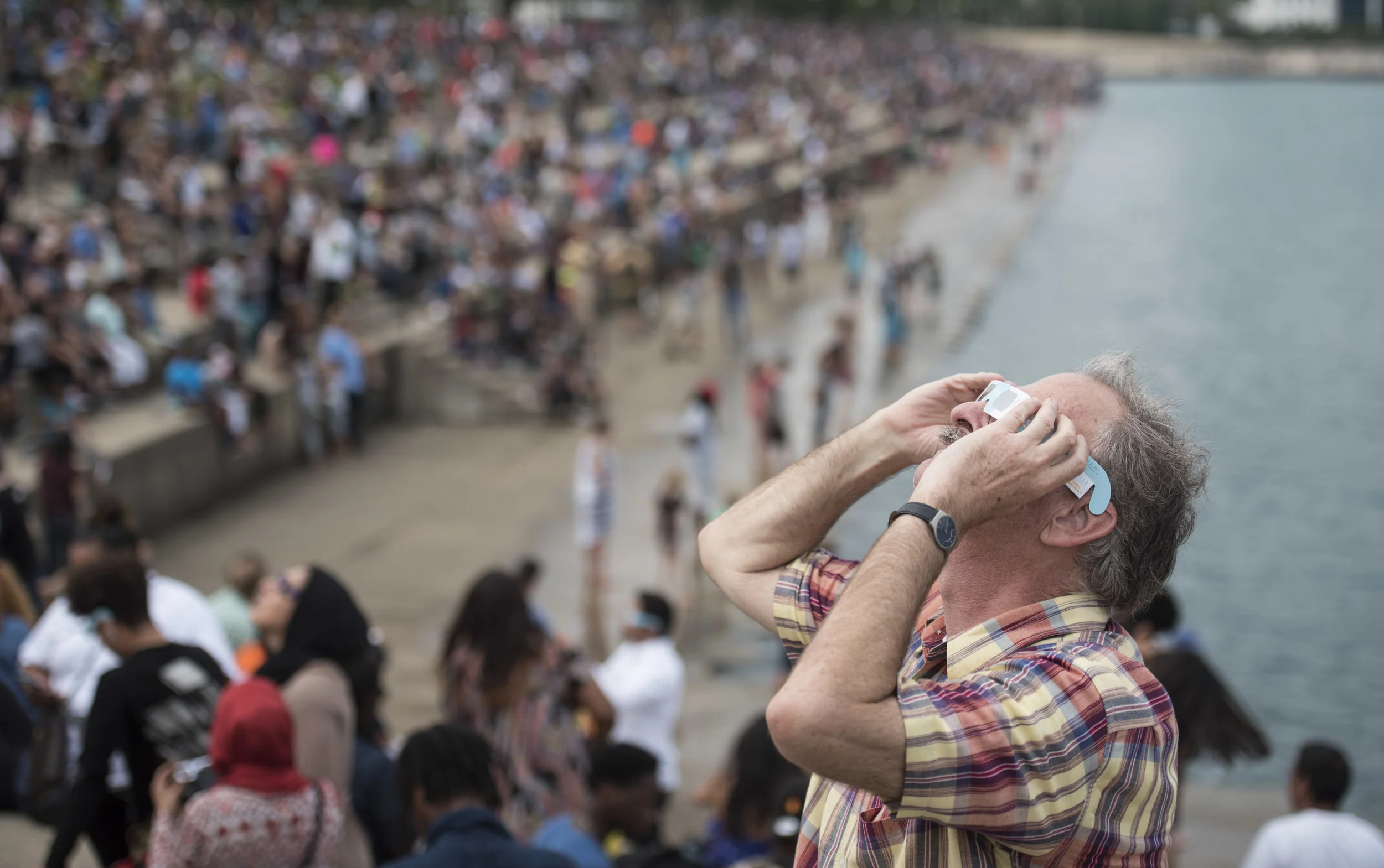 Tim Cash from Minneapolis took a break from his job to watch the solar eclipse outside Adler Planetarium, Monday, Aug. 21, 2017, in Chicago. (AP Photo/G-Jun Yam)