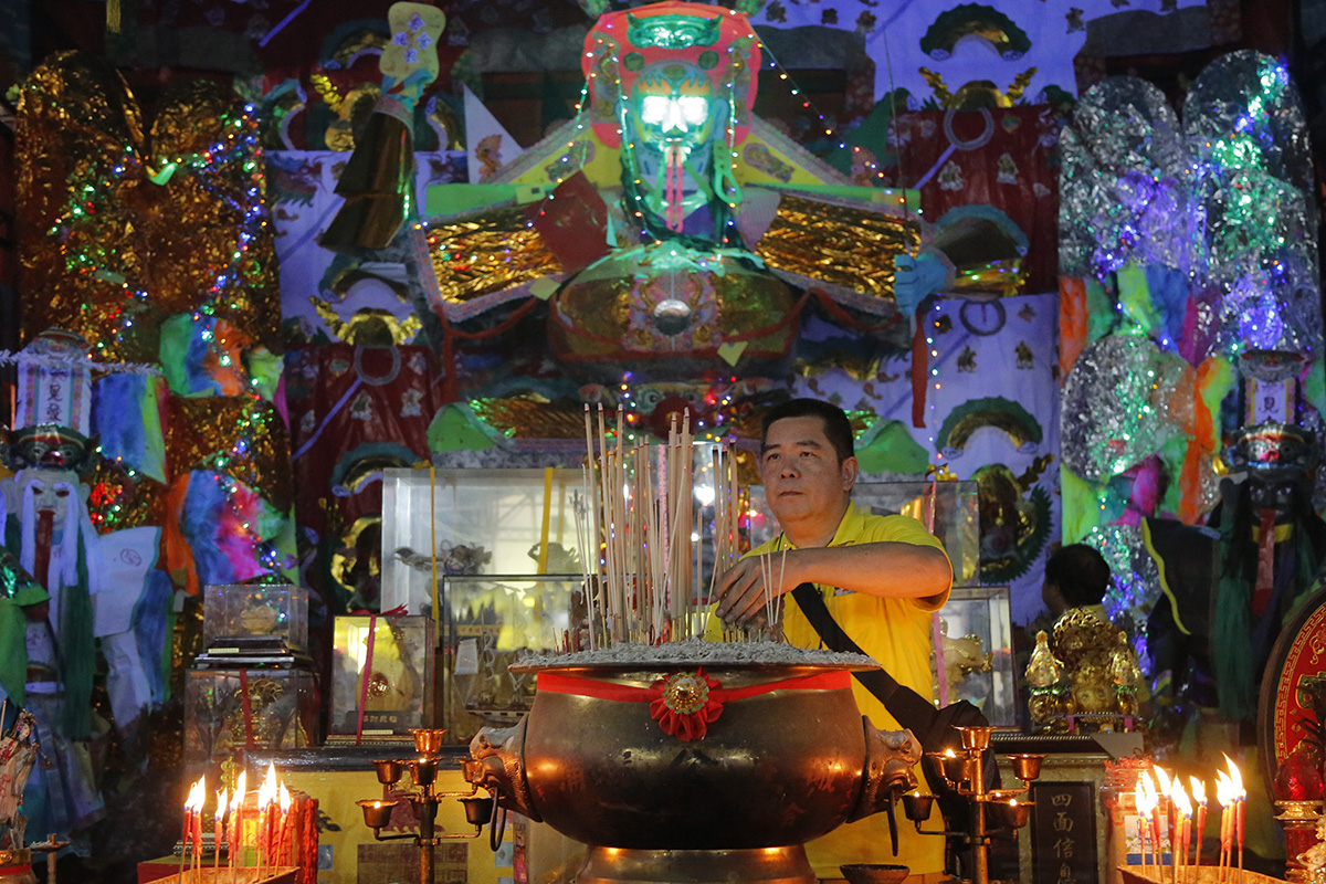 In this Aug. 16, 2018, photo, a man collects joss sticks in front of a giant paper statue of the Chinese deity "Da Shi Ye" or "Guardian God of Ghosts" during the Chinese Hungry Ghost Festival in Puchong, Malaysia. (AP Photo/Yam G-Jun)