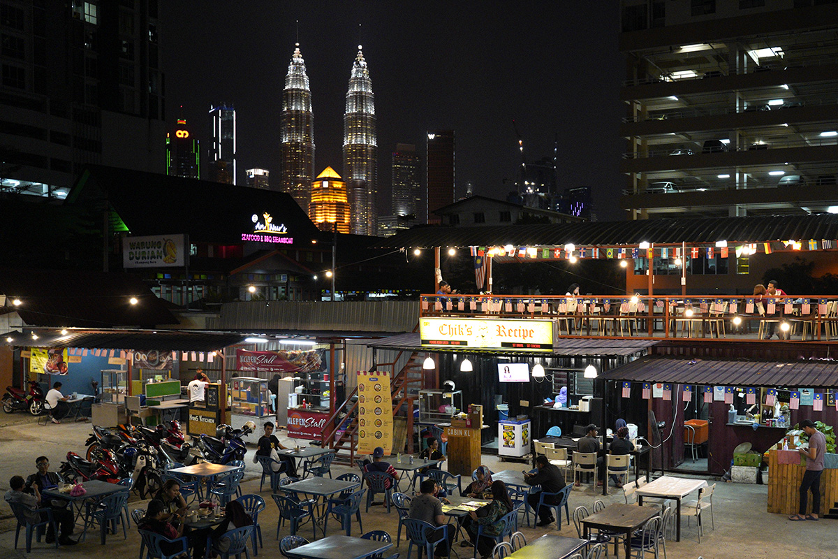 In this Thursday, Nov. 1, 2018, photo, Malaysia landmark building Petronas Twin Towers stands behind a cafe in Kampung Baru, Malaysia. (AP Photo/Yam G-Jun)