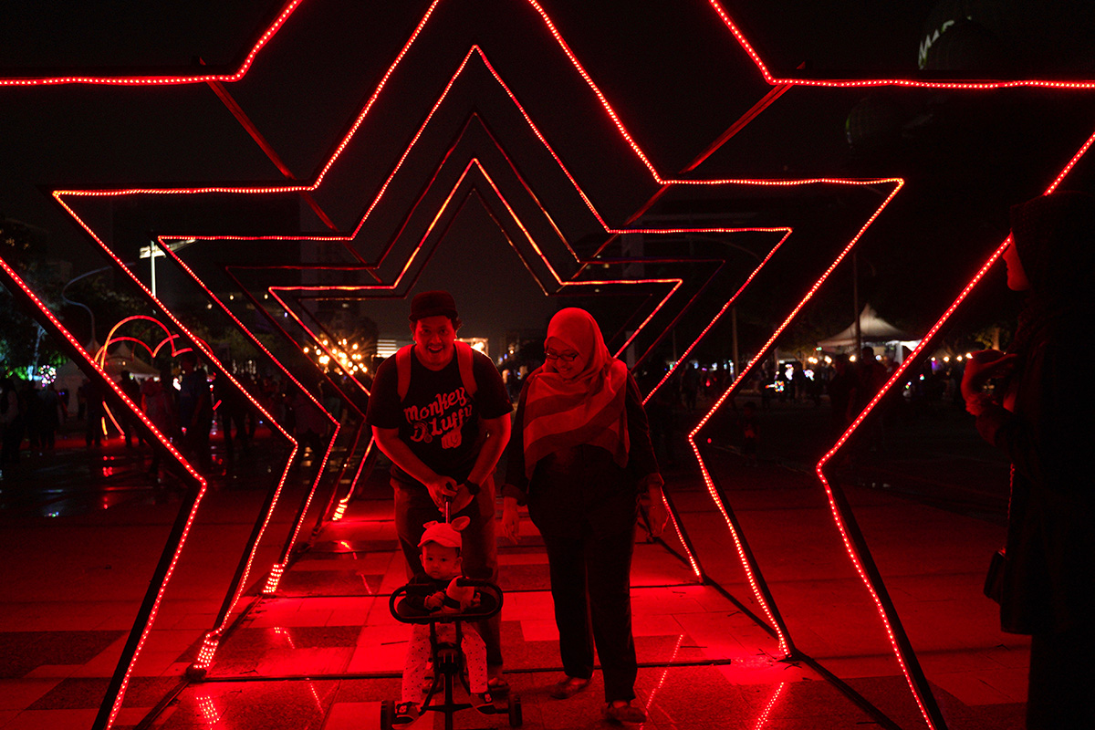 Festival goers walk through a light installation during the Light And Motion Putrajaya 2018 event in Putrajaya, Malaysia, Sunday, Dec. 30, 2018.(AP Photo/Yam G-Jun)