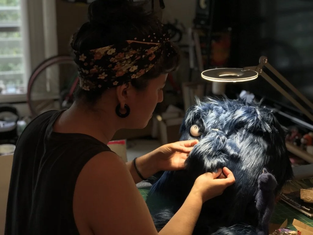 Risa sewing Harold, her right hand man – er, puppet – made out of fabric and ping pong balls.