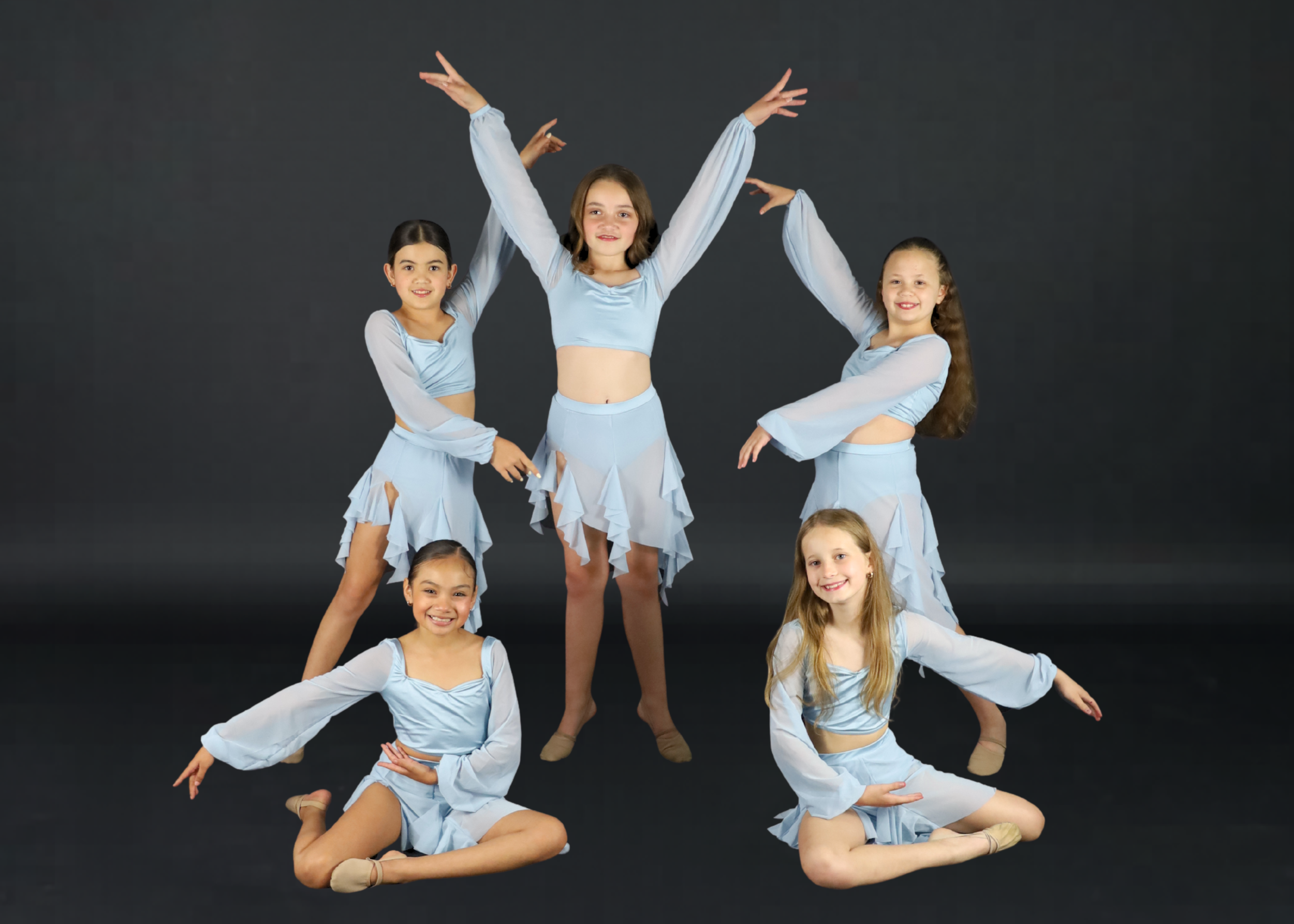 Group of six young girls in red and white dance costumes posing against a white backdrop.