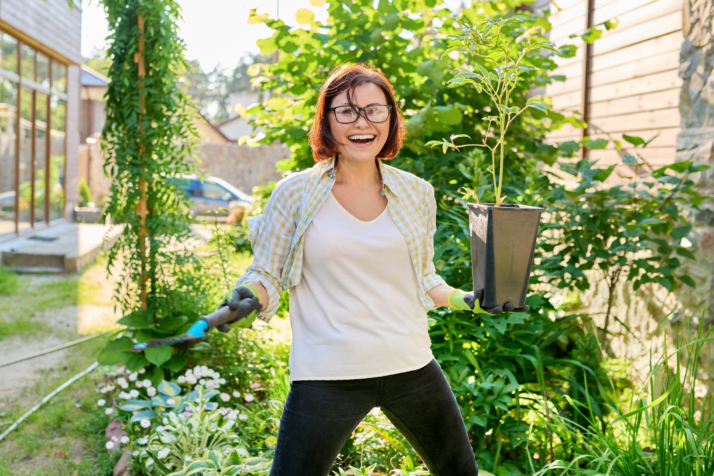 Garden Bliss: Smiling Woman with Wool and Plant in Her Garden - Garden City Dental Care