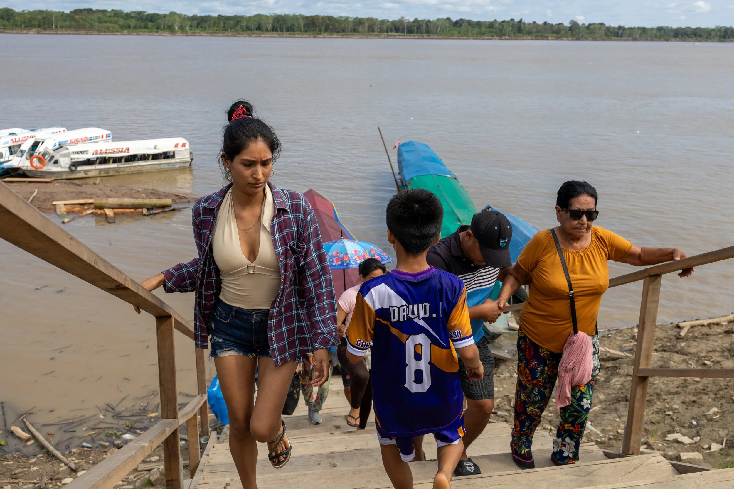 People stepping ashore from a small boat on a broad river