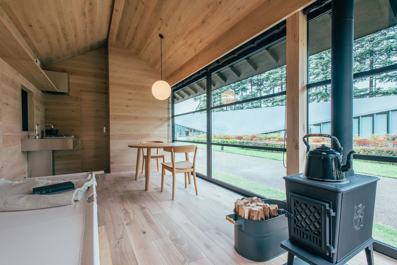 MUJI Hut prefab home designed by Jasper Morrison. Morrison's cork-clad structure features zones for cooking, eating, sleeping, and washing up.