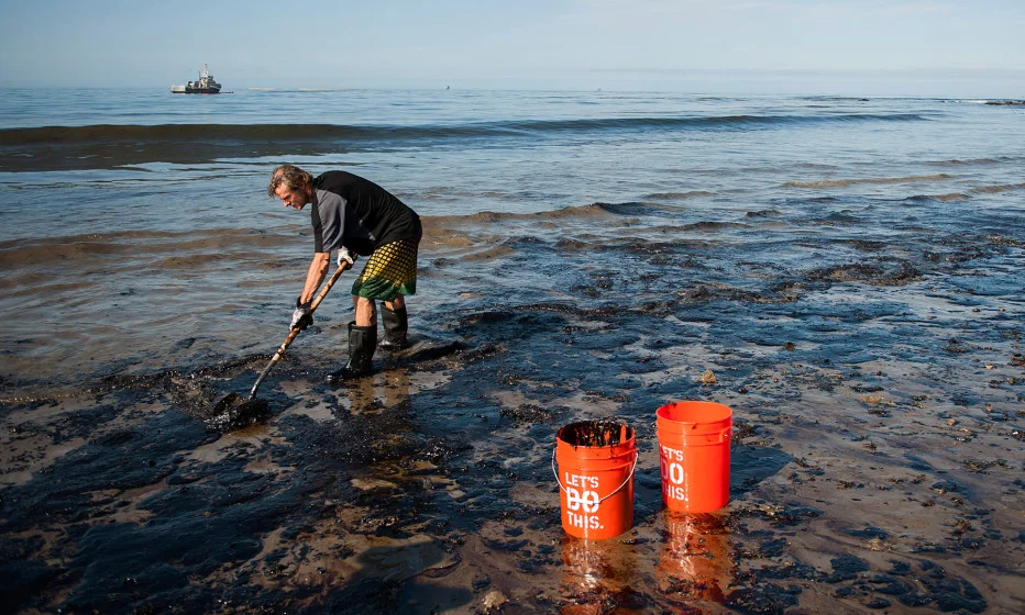 A man shovels up oil on a section of beach about a mile east of the Refugio oil spill in California, May 2015.
