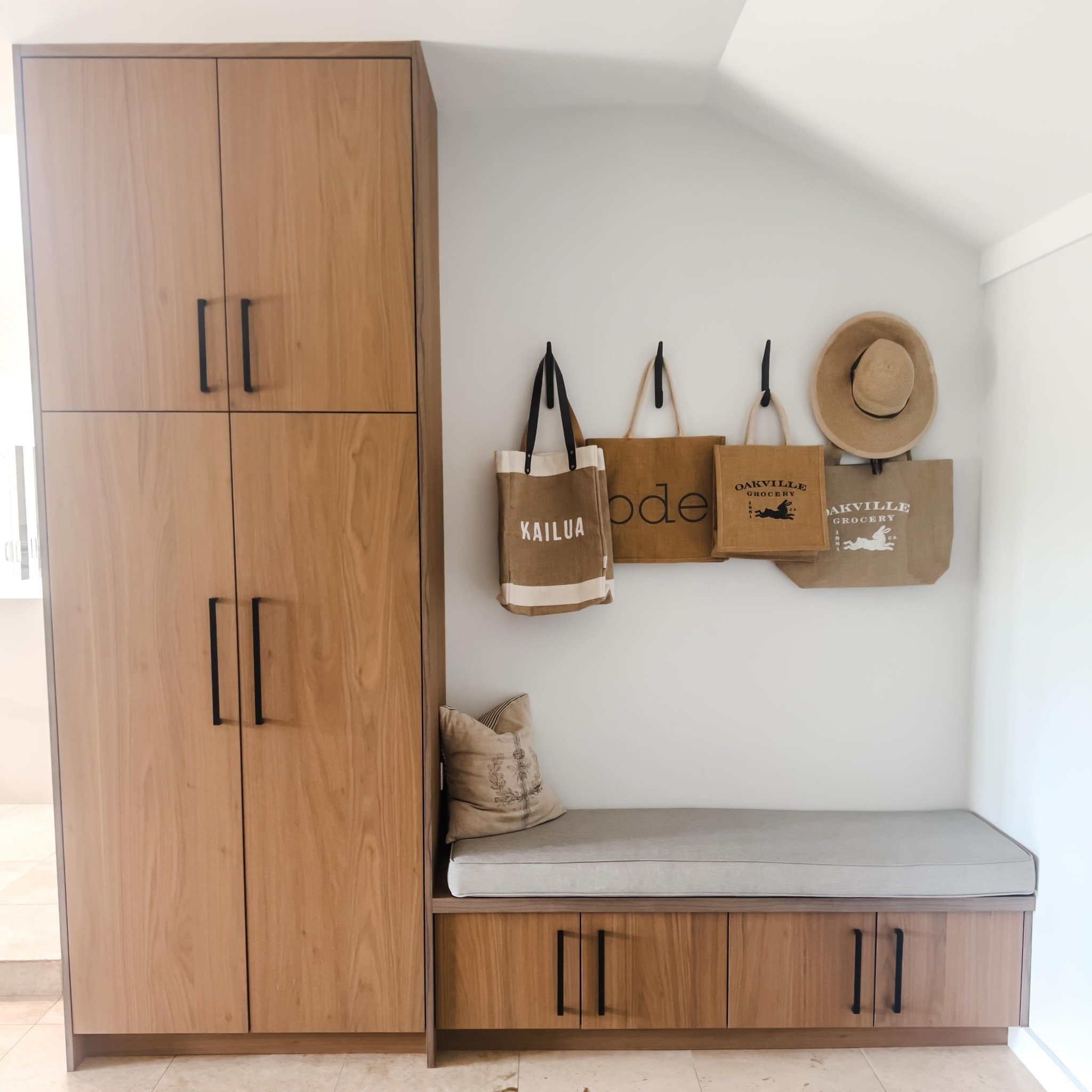 A beautiful multi-purpose spot, off the garage.  The tall Walnut cabinet doubles as an over-flow pantry and storage for miscellaneous items.  The bench cabinet keeps the family&rsquo;s footwear out of site while providing a comfortable seat for the k