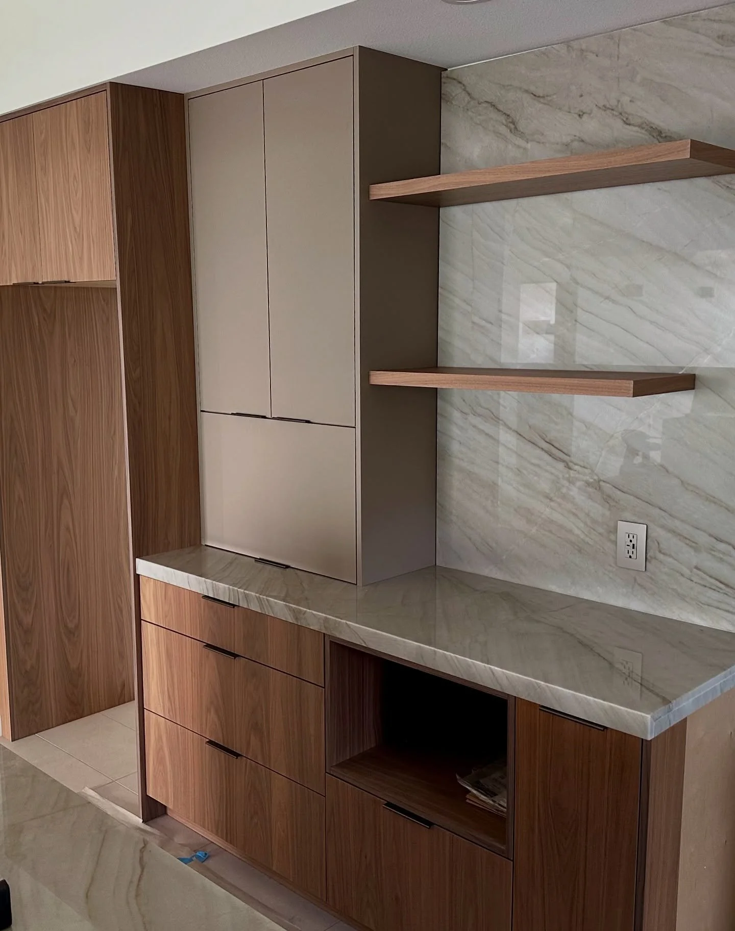 Kitchen in progress:  Our Walnut and Fenix combo with floating shelves and Blum Aventos lift hardware at the appliance garage. 

Main cabinetry:  custom frameless flat panel walnut (Shinnoki Frozen Walnut)
Accent cabinetry:  custom Fenix Castoro Otta