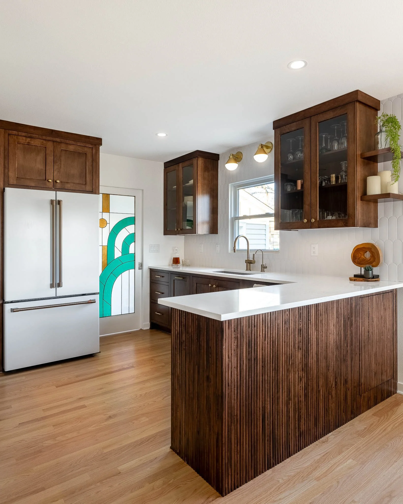 Dark walnut kitchen with white panel refrigerator, stained glass teal and gold Art Deco door panel, and fluted walnut island — Milwaukee Macpherson residential interior photography