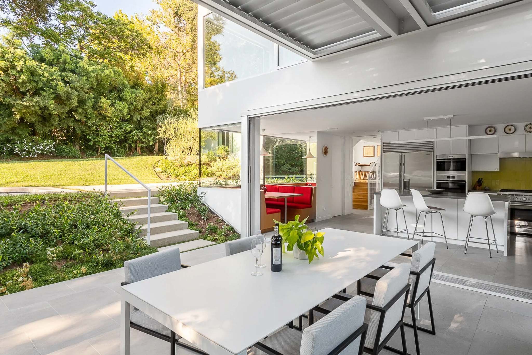 Covered indoor-outdoor living space with open glass walls, patio furniture, and lush landscaping — Milwaukee modern residence architecture photography
