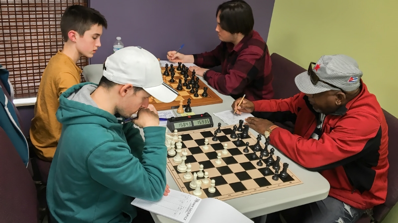 Final Round, Board One with Theo Slade (2039) (top left) playing white and Kai Tabor (2034) (top right) in control of the black pieces, with Kai going on to win the final round. Board Two has UCF Chess Club President Arnold Banner (1692) (bottom left) paired up with 2-time CFCC Club Champion Alfonso Gabbedon (2161) (bottom right) at the Club's UUUS tournament & training facility located near UCF.