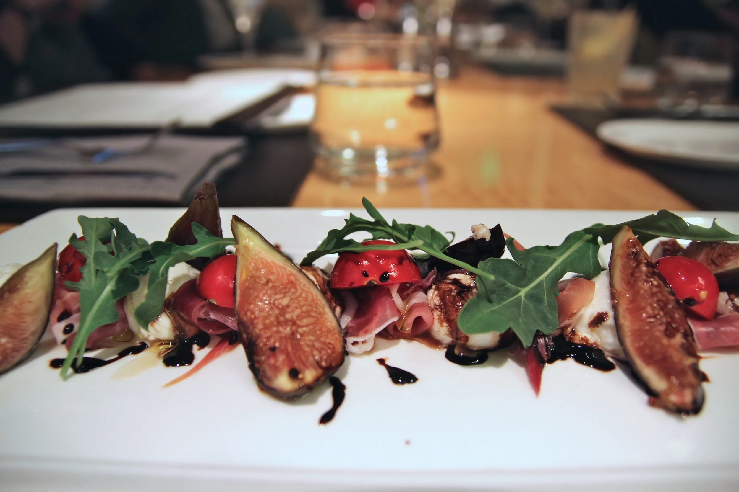 Burrata and grilled figs with prosciutto, cherry tomatoes and a balsamic reduction