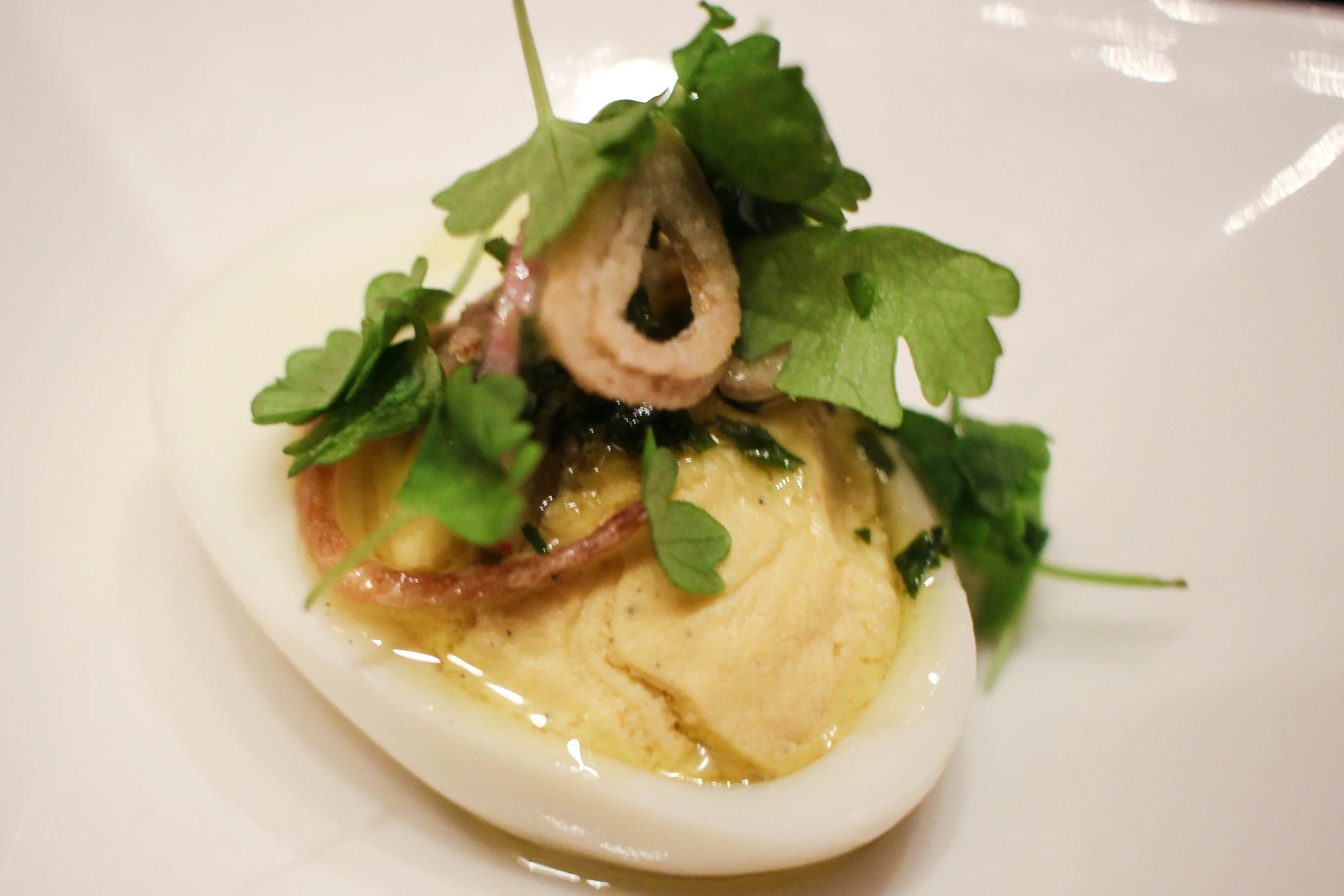 Deviled egg with salsa verde, breakfast radish, crispy shallot