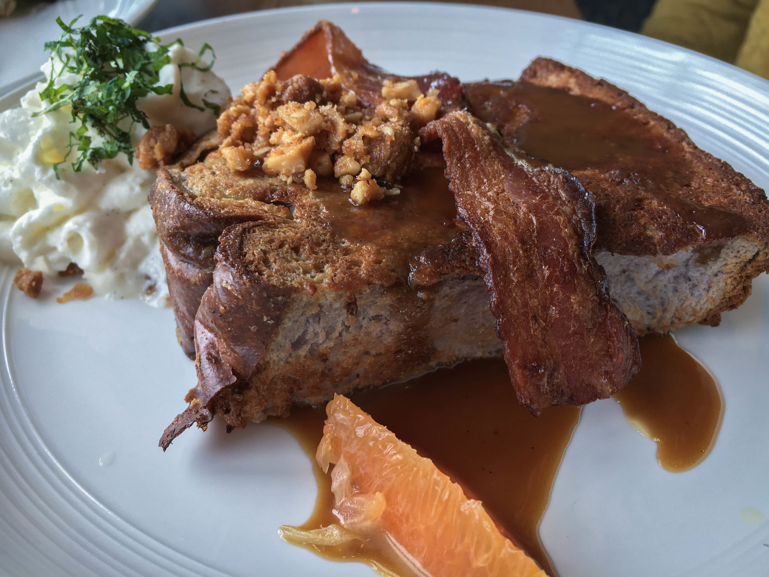 Punalu’u Bakery Taro French Toast with taro bread, apple wood smoked bacon, macadamia nut crumble, salted coconut caramel, fresh grapefruit, vanilla whipped cream, mint
