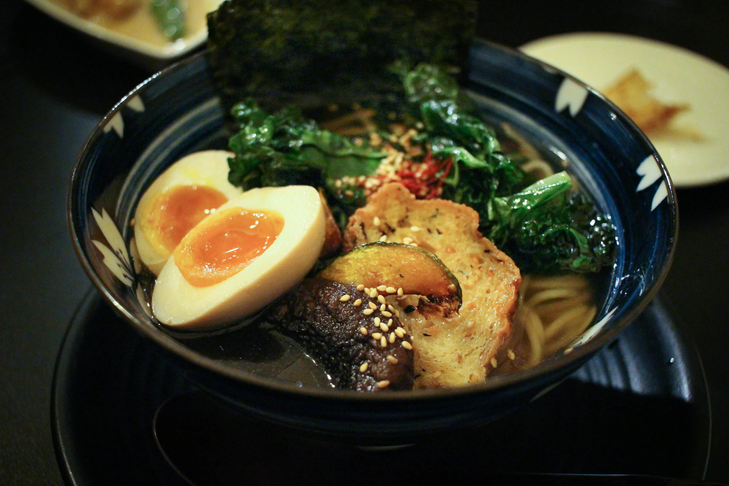 Veggie Ramen with tofu veg cake, bell pepper, fried kale, acorn squash, shitake mushroom, green onion and a soft-boiled egg. 