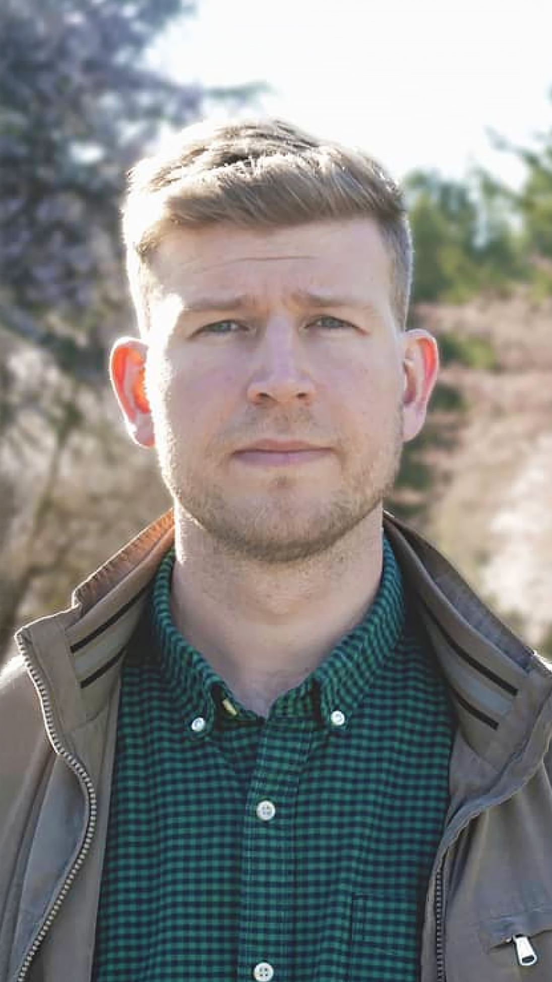 A portrait of a young man, Rico, a Vancouver and Richmond-based improv comedian and part of the improv comedy troupe 'Those Types', with light brown hair, blue eyes, outdoors on a sunny day.