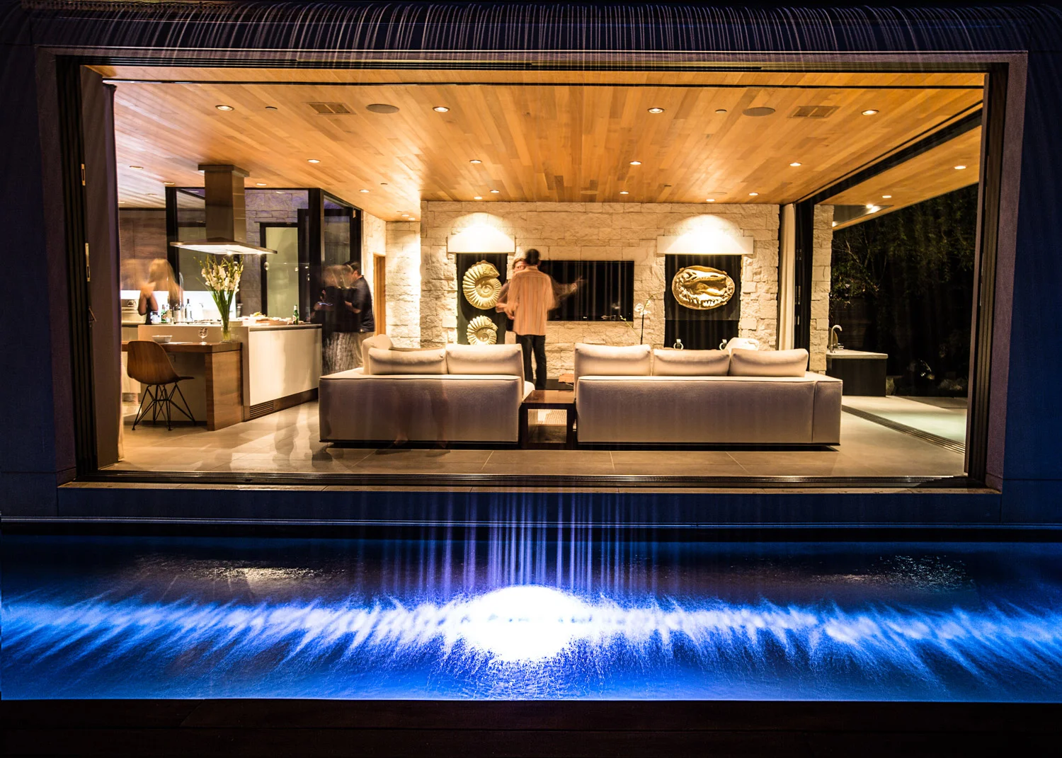 Acacia House modern Shangri-la custom pool waterfall feature creates the experience of a wave-like barrel over the living room