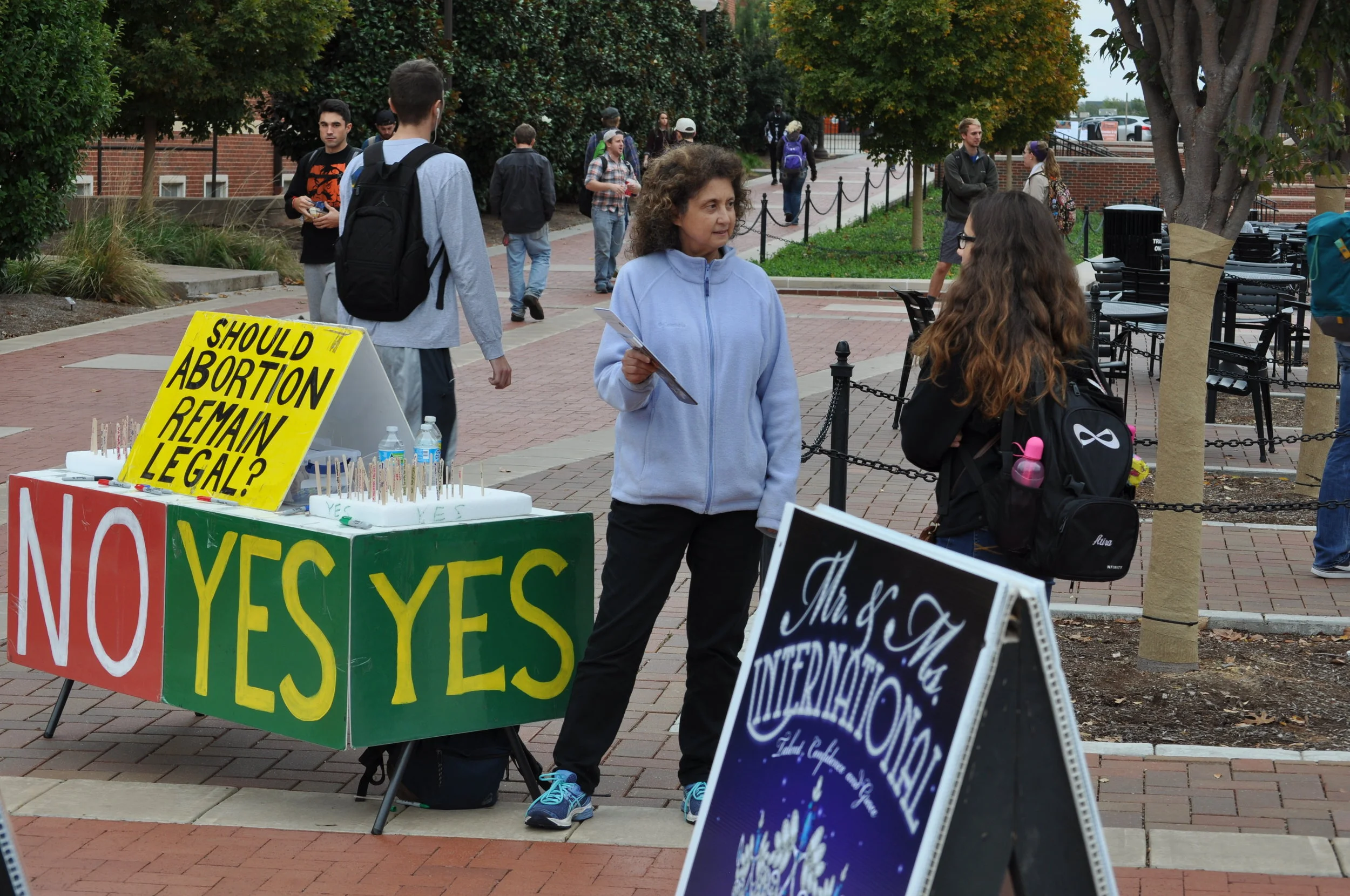 v\:* {behavior:url(#default#VML);}
o\:* {behavior:url(#default#VML);}
b\:* {behavior:url(#default#VML);}
.shape {behavior:url(#default#VML);} Tammy Cook interacts with a student near JFA’s experimental “popsicle poll” at OSU in November. Click here to see more pictures from the OSU November 2016 event, which included our large Art of Life Exhibit along with two new twists on our classic free speech board conversation tool.