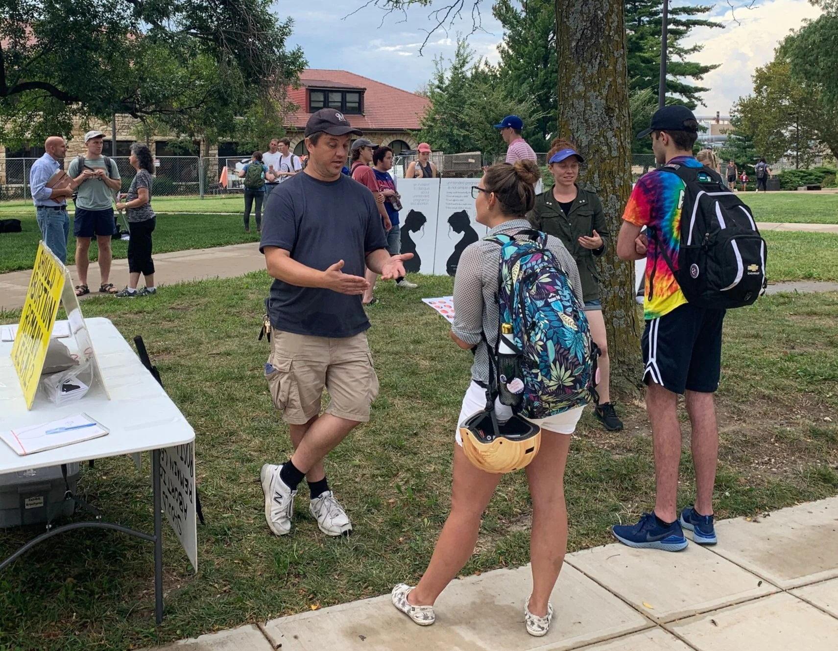 Thursday (KU): Paul Kulas (center) and volunteer Rebekah (second from right) interact with students near the poll table at KU.