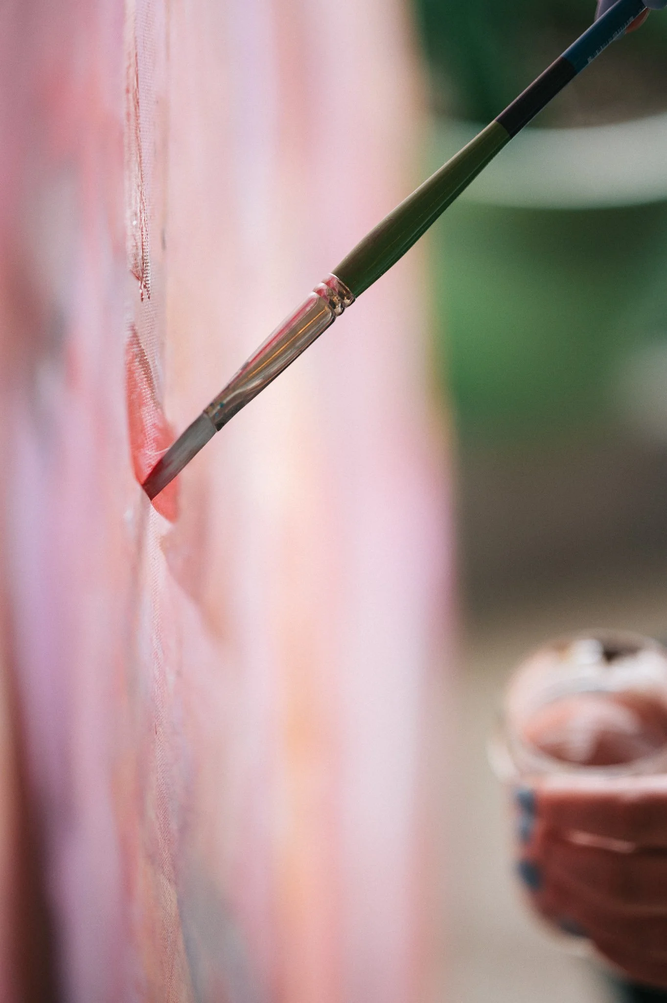 Close-up of pink paint being applied to canvas with a brush during an art experience