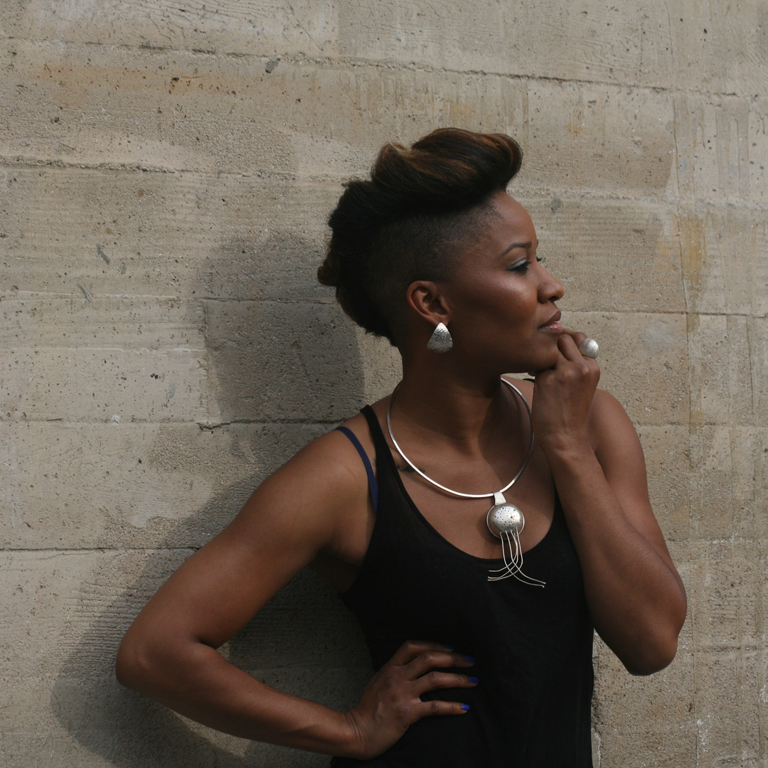 Three statement jewelry pieces in silver and gold shine on beautiful Tomi.