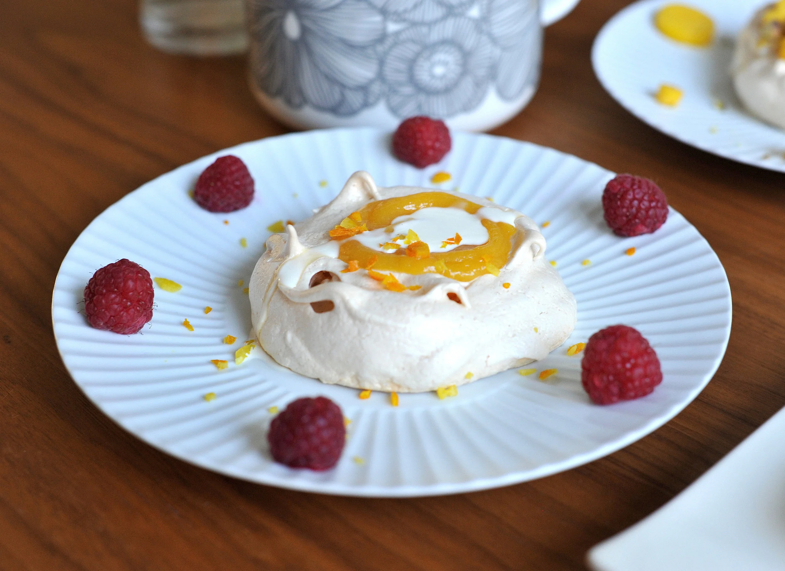Meringue topped with lemon curd, zest of lemons and oranges served with raspberries and cream © Photography by Emmerline Smy