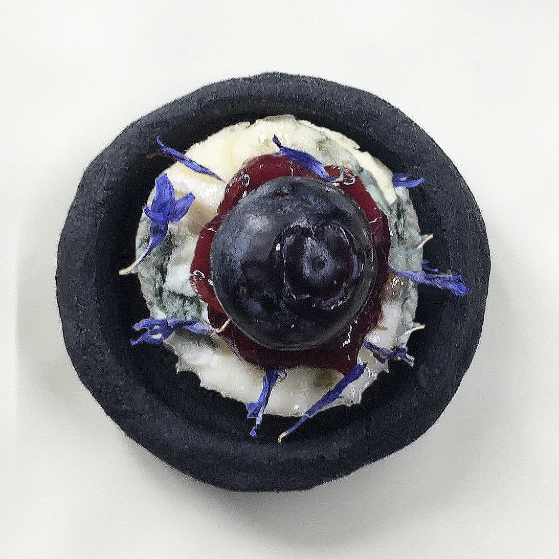 Charcoal biscuit with gorgonzola cheese, quince & blueberry paste, pickled blueberry and dried cornflower garnish.