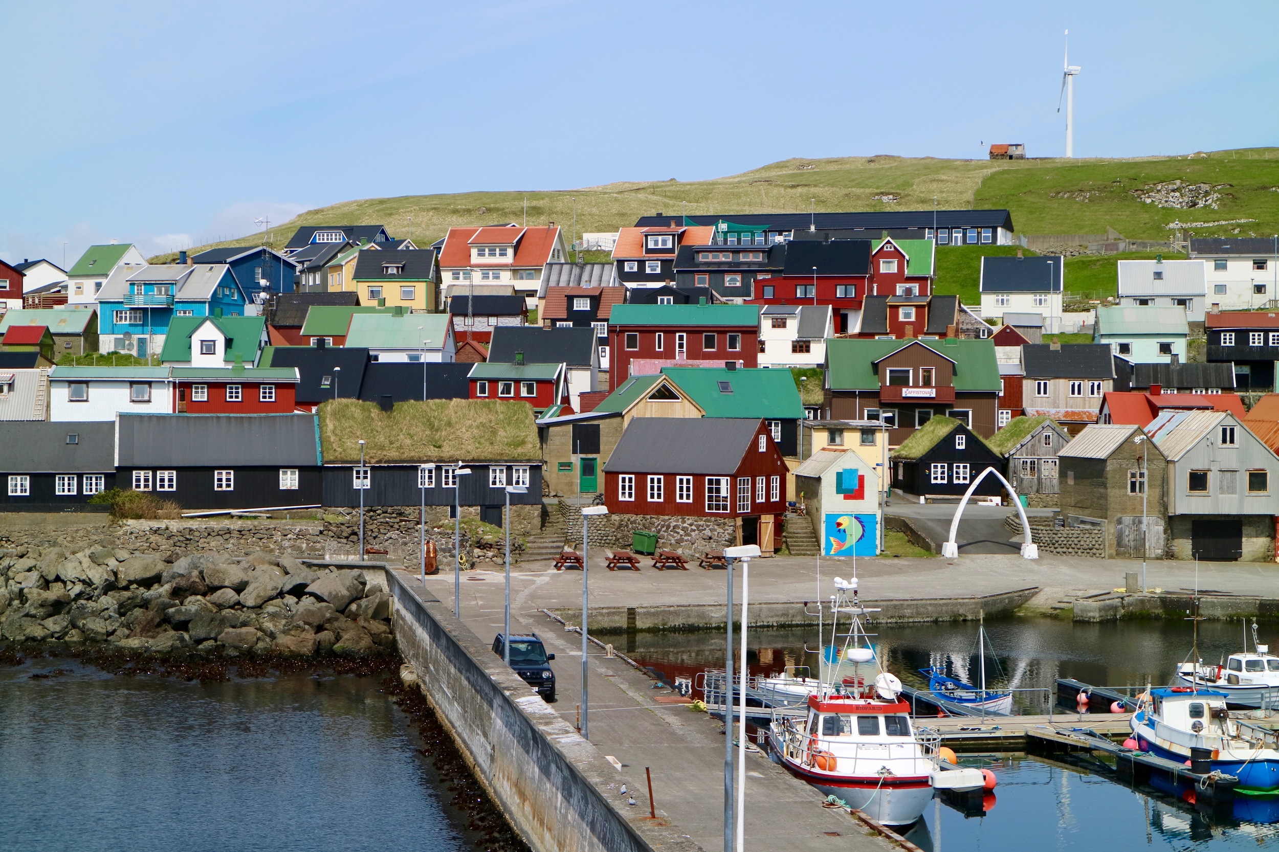 As soon as the ferry M/F Ternan approaches the harbor, you can spot the red brown house with the white window frames, close to the gate made out of whale-jawbone. That's where you will meet Tjóðhild, Anna Malan and Barbara.