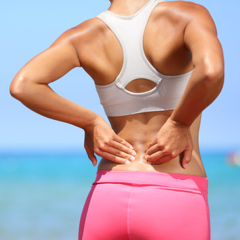 Fit woman holding her lower back in pain after physical activity – therapeutic massage for back pain relief in Leesburg and Ashburn VA