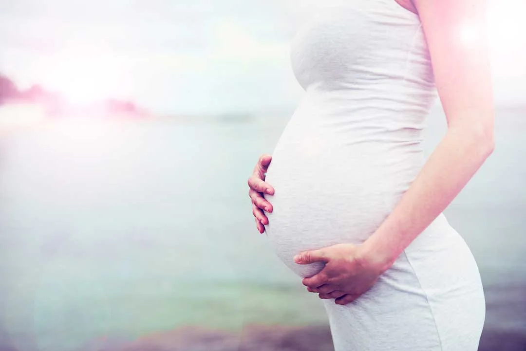 Pregnant woman gently holding her belly during a serene moment – representing the comfort and relief many clients seek through prenatal massage at Massage Hope in Leesburg and Ashburn VA