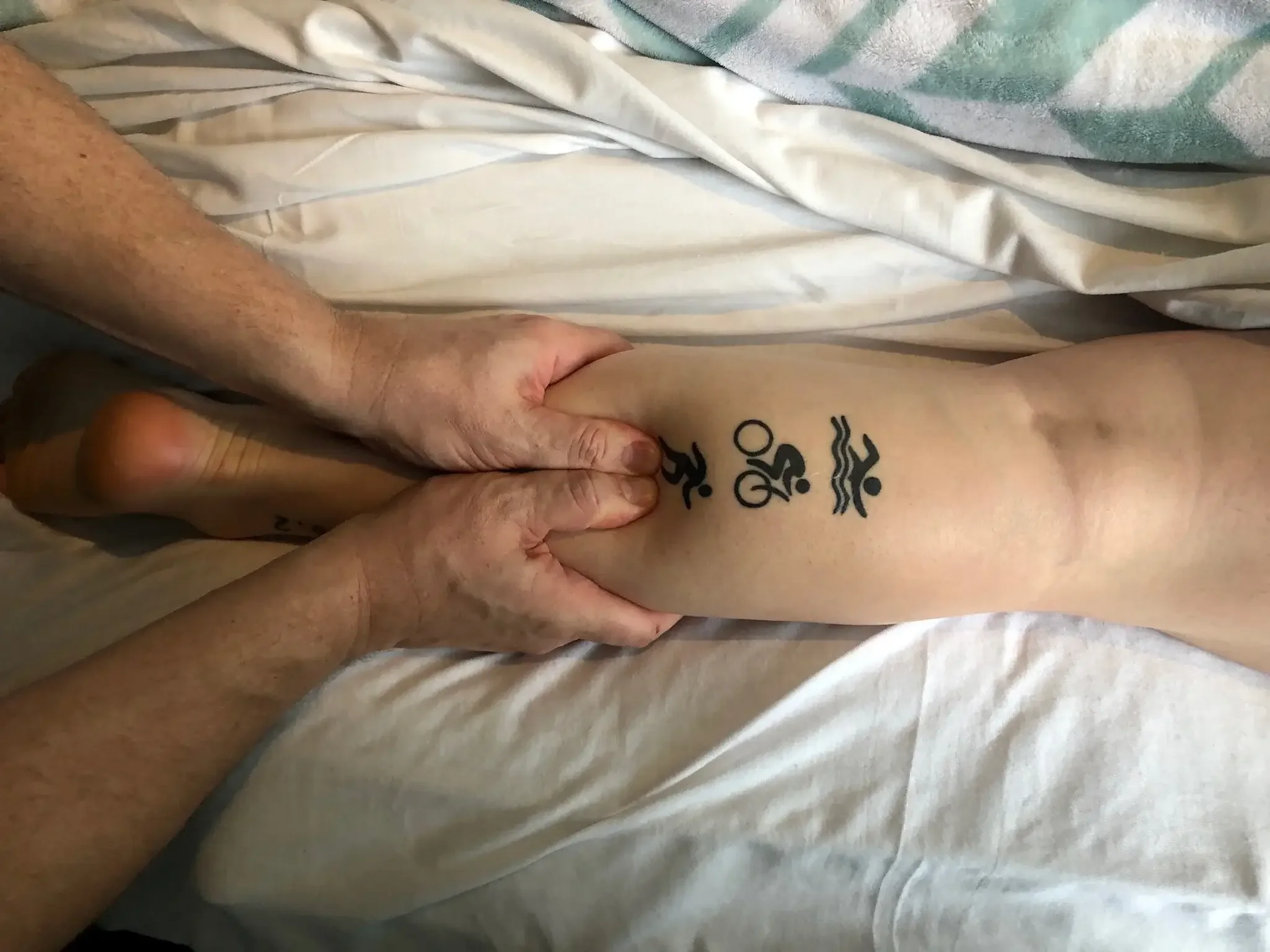 Therapist performing targeted calf and lower leg massage on an athlete with runner, cyclist, and swimmer tattoos – sports injury recovery and athletic massage at Massage Hope in Leesburg and Ashburn VA