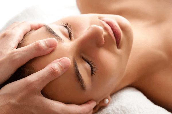 Licensed massage therapist performing gentle temple and forehead massage on a relaxed client for migraine and tension headache relief at Massage Hope in Leesburg and Ashburn VA