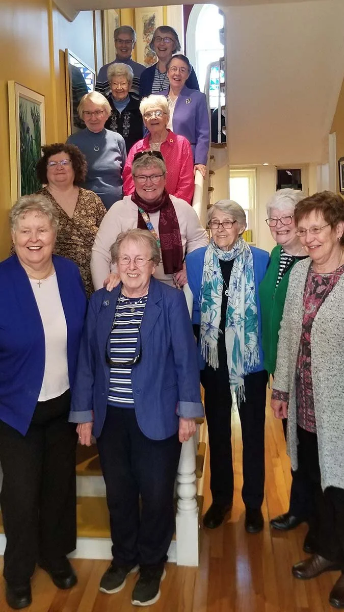  Nineteen years after the Presentation Sisters sold their convent and left Witless Bay, 13 of them, five of whom were former residents, returned for afternoon tea. The reunion, organized by the Heritage Committee of Witless Bay, had been planned for last November but was postponed due to a case of COVID, and a hoped-for visit on Valentine’s Day was delayed due to a winter storm. Finally, it proceeded on a sunny Saturday, May 13. On arrival, the sisters were greeted by members of the Heritage Committee. Also attending were several local residents, some of whom were taught by the sisters, who graciously volunteered to help with Heritage Committee events. &nbsp;After being encouraged to leave the kitchen where all migrated upon entering the house, they were escorted to the second storey chapel where Heritage Committee Co-Chair Maureen Walsh and member Colleen Hanrahan described the committee’s activities since its formation in 2004, and the role the former convent played. The youngest member of the Committee, Chelsea Green, delivered a solo rendition of Patsy Cline’s  Walking After Midnight  to an appreciative audience including her grandparents, parents and brother. Following this, all were invited to the dining room for tea, sandwiches, and sweets. The afternoon ended with a singalong accompanied with live accordion music. “In all, it was a wonderful afternoon in a historic setting which the Irish Presentation Sisters first occupied in 1860,” said Walsh. Above, starting at the top of the stairs and going from left to right are: Sr. Doris Walsh, Sr. Sheila Leonard, Sr. Margaret Mary Gosse, Sr. Marie Furey, Sr. Francis Pennell, Sr. Mary Molloy, Sr. Helen Martinez, Sr. Mary Rossiter, Sr. Betty Quinlan,&nbsp;Sr. Marilyn Doyle, Sr. Mary Dower, Sr. Roisin Gannon, and Sr. Clo Martin. Missing from the photo&nbsp;is Sr. Martina O'Reilly, who is also a former student. 