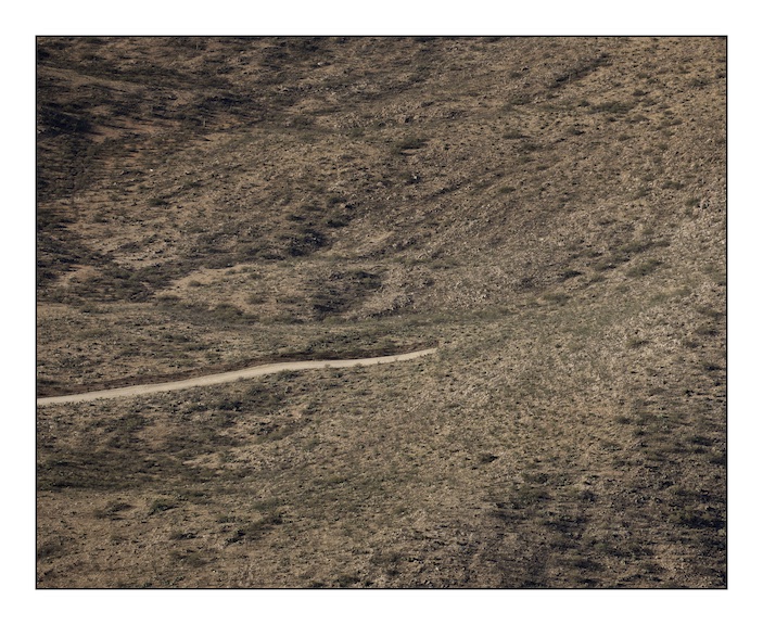 The border fence between Mexico (above) and the United States (below) stops abruptly as the Baboquivari Mountains rise out of the desert near the hard scrabble town of Sassabe that straddles the border in southern Arizona. The fence costs over one million dollars per mile and in areas where the terrain is especially harsh and dangerous to cross the construction halts. The consequence of this is that migrants are forced into areas where human life is incredibly difficult to sustain and they die. 