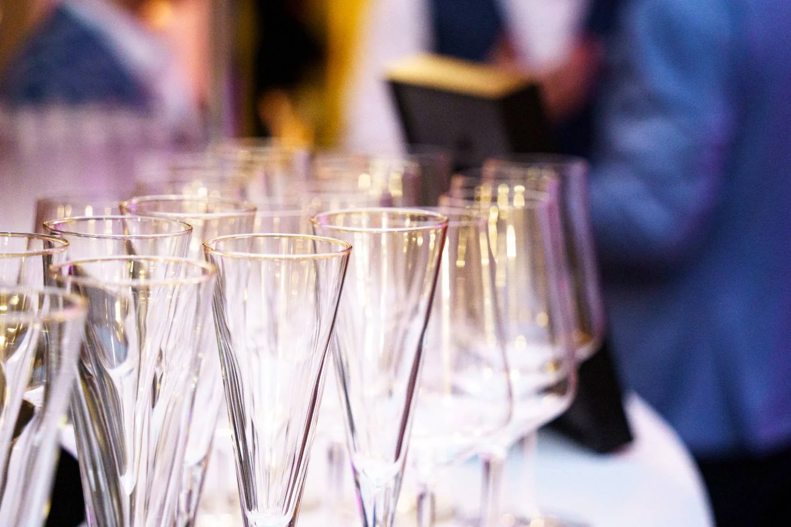 A row of empty champagne glasses on a table at a social event or celebration.