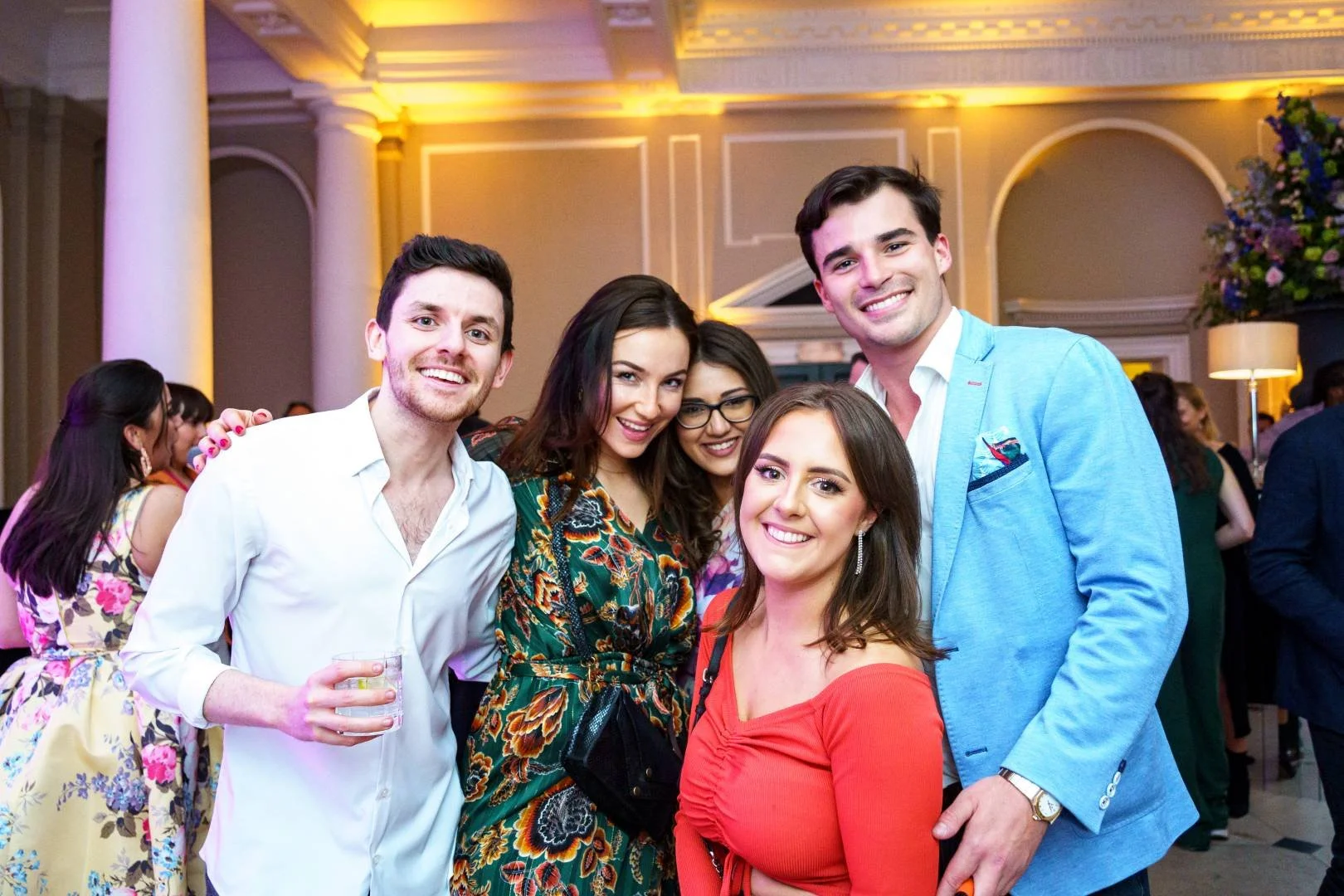 Group of five people smiling at a party or social event.