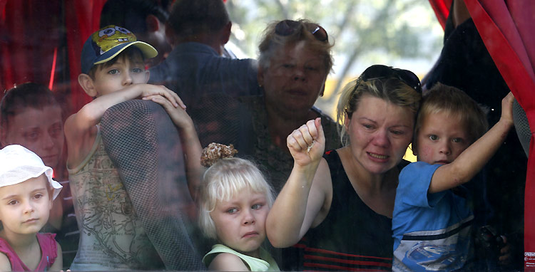 Residents of the eastern Ukrainian region of Donetsk look out of a bus window as they prepare to depart to escape the fighting. ©Reuters/M. Zmeyev