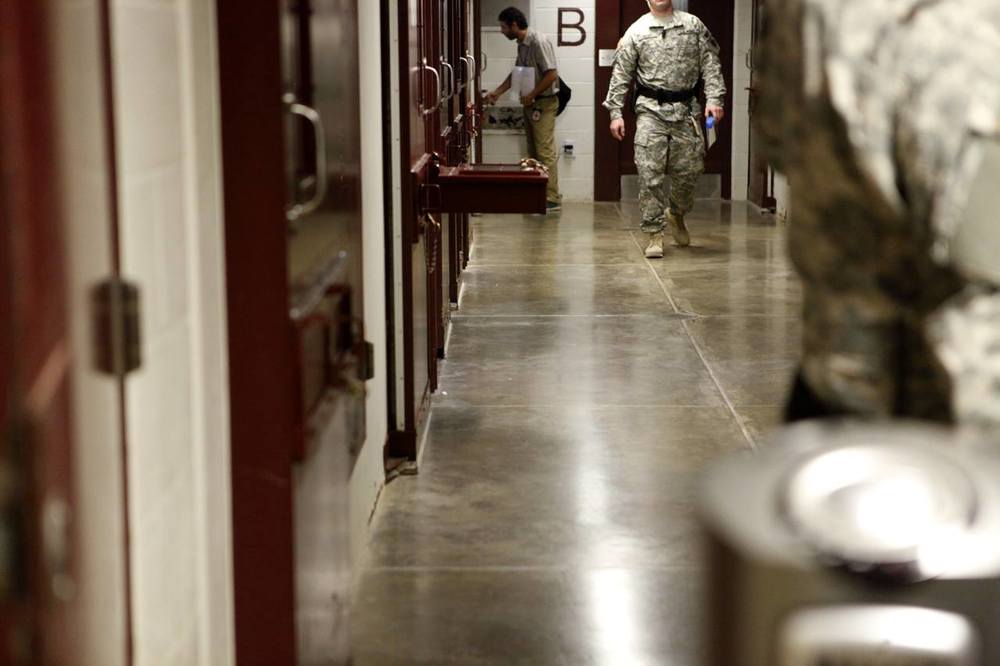 In this image, you can see an ICRC delegate in GTMO shaking hands with a detainee through the cell’s “bean hole”. Copyright: Anna Nelson/ICRC