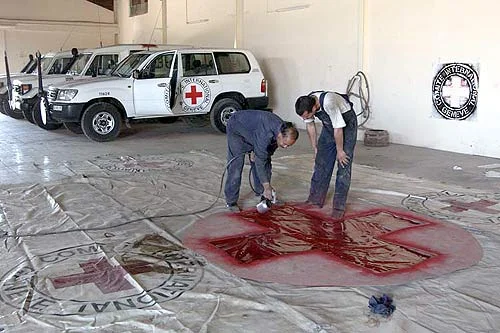 ICRC employees in Amman painting a large emblem on a tarpaulin intended to cover trucks bringing aid from Jordan to Iraq.