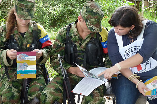 Guaviare state, San José del Guaviare. An ICRC delegate speaks with members of FARC-EP (Revolutionary Armed Forces of Colombia) while they peruse ICRC brochures, during a dissemination session on international humanitarian law (IHL). © ICRC / B. Mosquera / co-e-01956