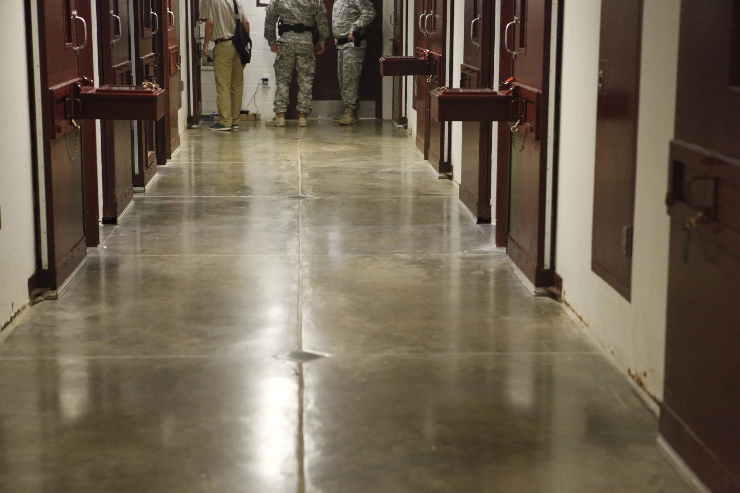 In this image, you can see an ICRC delegate in GTMO shaking hands with a detainee through the cell’s “bean hole”. Copyright: Anna Nelson/ICRC 