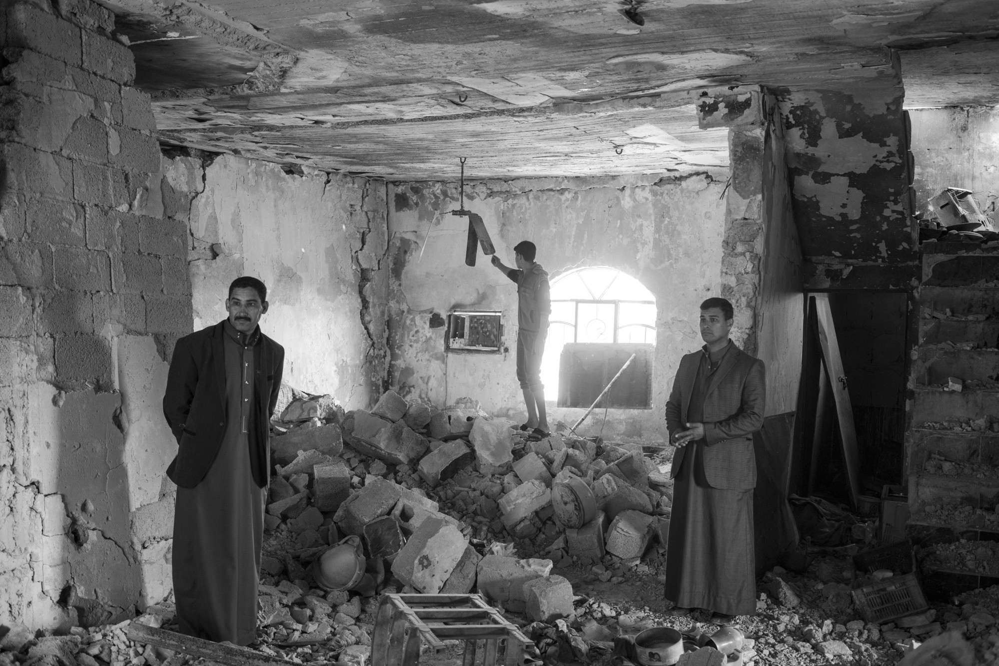 A family surveys the damage to their house in Albu Ajeel, which was bombed by armed groups as they retreated from the area last year. Moises Saman/Magnum Photos for ICRC