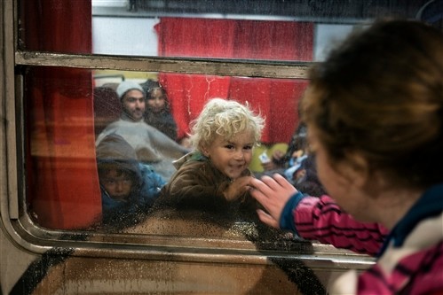 A child waves to a Slovenian Red Cross member just before the train departs for Austria. ©Thomas DWORZAK/ICRC