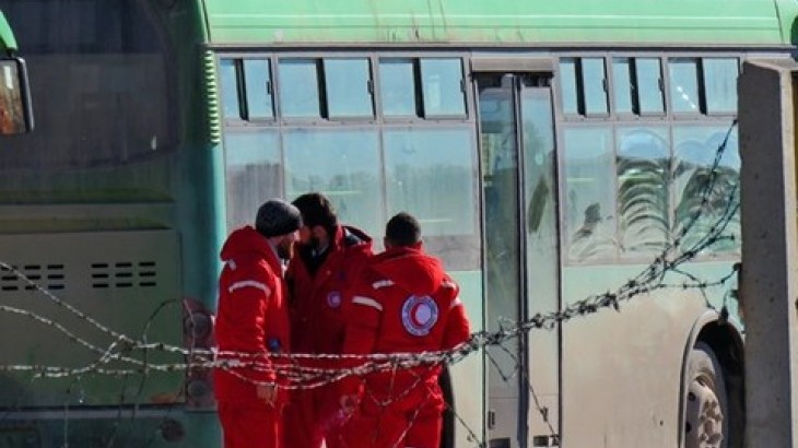 Syrian Red Crescent workers stand next to buses used to evacuate civilians from East Aleppo. 2016 /AFP Stringer