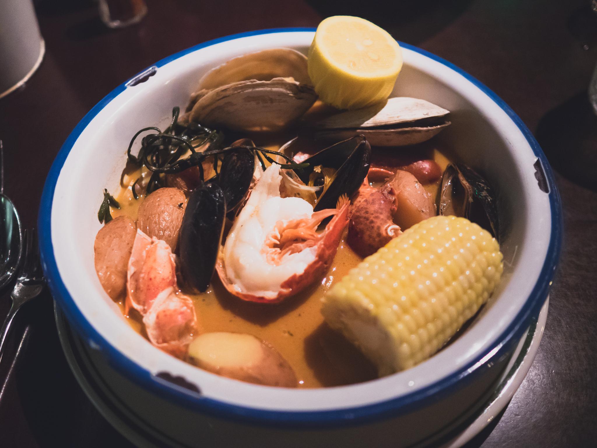 new england boiled dinner with mussels, steamers, lobster, linguiça, potatoes, steamed corn.