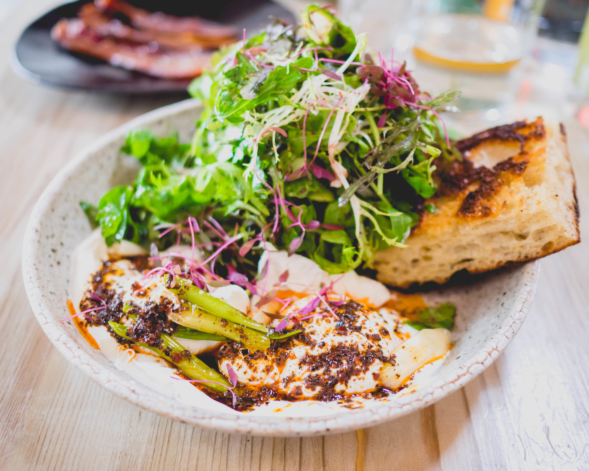 turkish eggs : poached farm eggs, aleppo-urfa butter, garlicky sheep's milk yogurt, charred scallions, lemony salad & cornmeal focaccia.