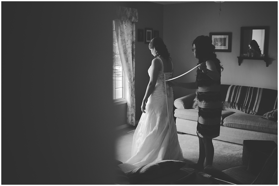 bride getting ready in living room. A stunning Fall wedding in Lethbridge Alberta - a religious church ceremony at the URC Church with stained glass windows, a quick stop at the Wooden Shoe for lunch and bridal party pictures at Indian battle park. #albertawedding #lethbridge #redwinewedding #redcolourscheme #babiesbreathboquet #indianbattlepark #woodshoe #overcastwedding #fallwedding #kissingcouple #brideandgroom #emotionalwedding #church #churchceremony